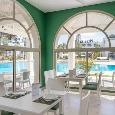 Pizzeria La Pergola lumineuse offrant une vue panoramique sur la piscine de l'hôtel à Djerba.