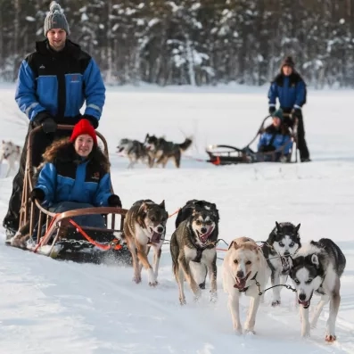 Deux personne qui font l'activité traîneau à chiens de neige 