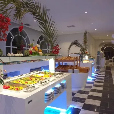 Buffet de restaurant illuminé proposant des plats variés et du pain frais à l'hôtel Djerba Golf.