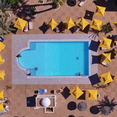 Vue aérienne d'une piscine d'eau de mer avec parasols jaunes, idéale pour la thalassothérapie à Djerba.