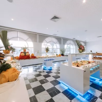 Salle de restaurant lumineuse au sol damier avec buffets garnis de spécialités culinaires à Djerba Golf.