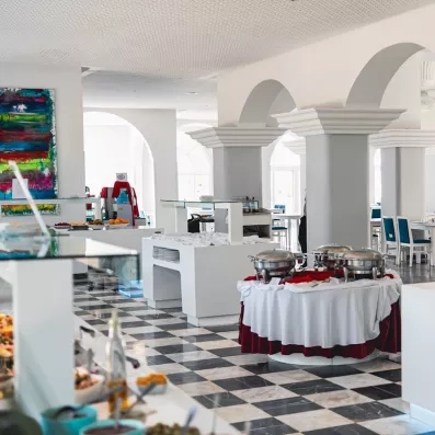 Buffet spacieux et moderne de l'hôtel Djerba Golf sous des arcades blanches traditionnelles pour un séjour gastronomique.