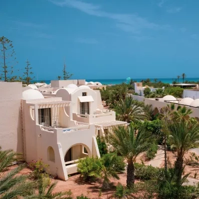 Architecture mauresque des bungalows blancs face à la mer turquoise sous le soleil de Djerba, Tunisie.