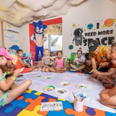 Atelier de peinture pour enfants sur tapis coloré avec animateur et décor ludique.