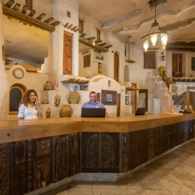 Comptoir de réception en bois sculpté avec décorations artisanales et deux réceptionnistes.