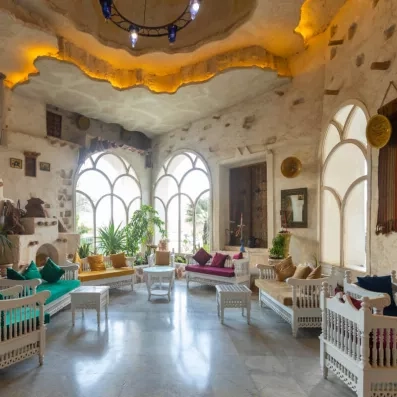 Salon méditerranéen avec arches lumineuses, canapés blancs et décorations traditionnelles orientales.