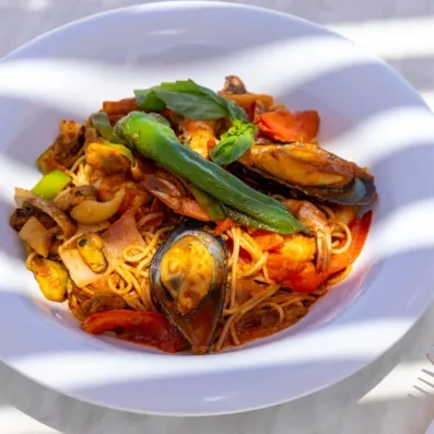 Assiette de pâtes aux fruits de mer avec moules, crevettes, légumes et sauce tomate.