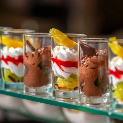 Verrines dessert colorées avec mousse, fruits frais et coulis rouge en présentation soignée.