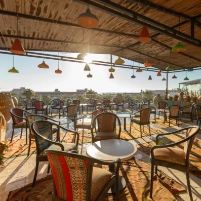 Terrasse extérieure colorée avec chaises rembourrées, lampes suspendues et ambiance chaleureuse.