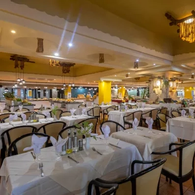 Salle de restaurant élégante avec tables dressées, éclairage chaleureux et buffet en arrière-plan.