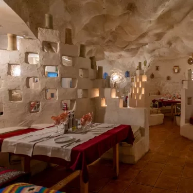 Restaurant décoré façon grotte avec murs sculptés, tables dressées et ambiance chaleureuse.