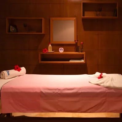 Table de massage zen avec fleurs d'hibiscus au centre spa du One Resort Aqua Park à Monastir.