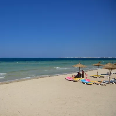 Plage de sable fin et parasols en paille au bord de la Méditerranée à Monastir.