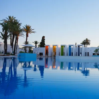 Grande piscine extérieure design entourée de palmiers au coucher du soleil au One Resort Aqua Park.