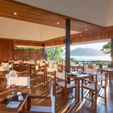 Salle de restaurant en bois, sur la terrasse offrant une vue sur l'océan.