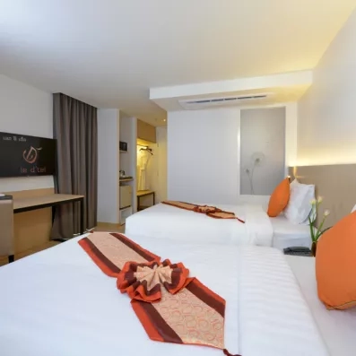 Une chambre avec un coin bureau et des touches décoratives sur les deux lits doubles.