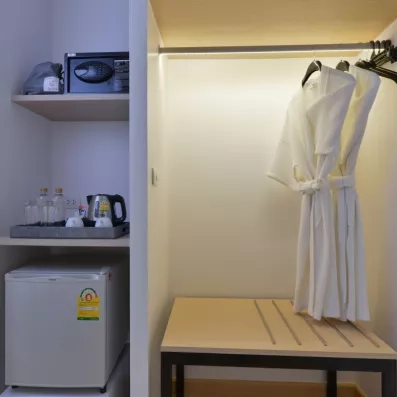 Un espace de rangement incluant un minibar et une penderie avec des peignoirs.