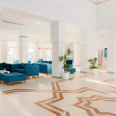 Lobby spacieux et lumineux du One Resort Aqua Park à Monastir avec canapés bleus et sol marbré.