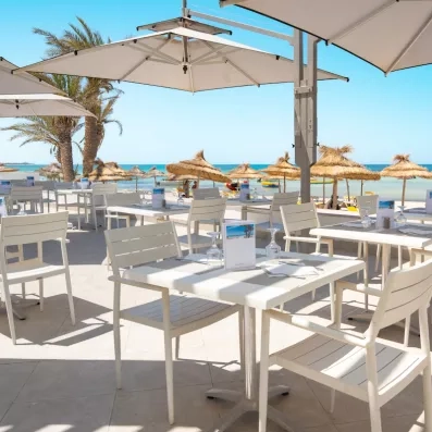 Terrasse du restaurant de plage Sporting Beach offrant une vue panoramique sur les eaux turquoise de Djerba.