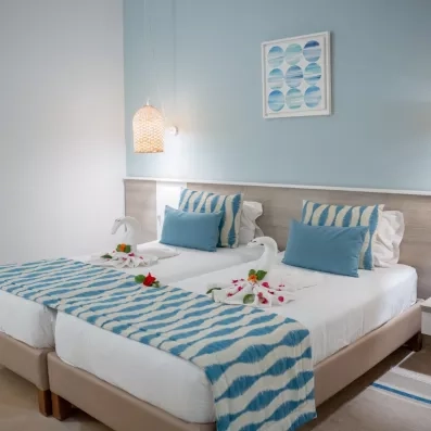Chambre double élégante à l'hôtel Ulysse Djerba décorée de cygnes en serviettes et de touches bleues.