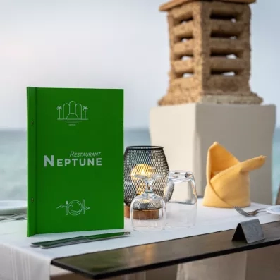 Menu du restaurant Neptune sur une table élégante face à la mer à l'hôtel Ulysse Djerba.