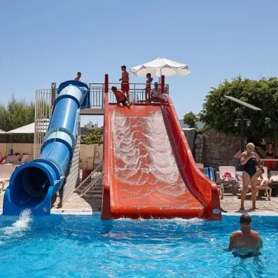 tobbogans couvert bleu et blanc, découvert rouge, enfants qui jouent dans les toboggans, personnes qui se baignent et qi bronzent sur les transats 