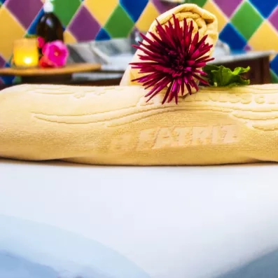 Un gros plan sur une table de massage préparée avec une serviette jaune et une fleur pourpre.