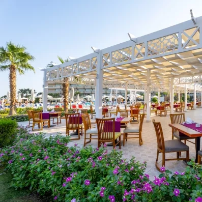 Pergola fleurie et tables dressées en extérieur près de la piscine au Seven Seas Jolie Bay.
