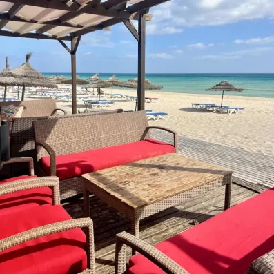 Espace lounge en rotin avec vue directe sur la plage turquoise