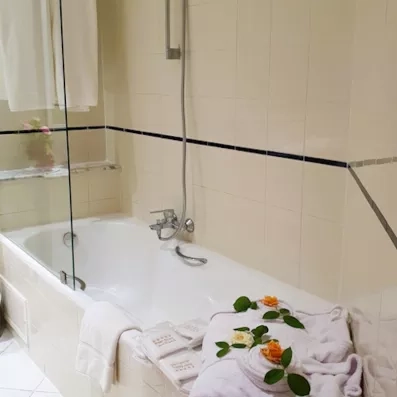 salle de bains avec baignoire avec deux peignoirs et des fleurs 