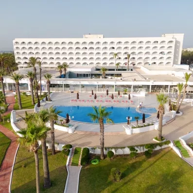 Vue aérienne des piscines et terrasses du One Resort Jockey Monastir, complexe hôtelier pieds dans l'eau.