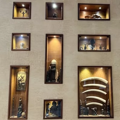 Mur décoratif avec niches éclairées exposant sculptures et objets artisanaux
