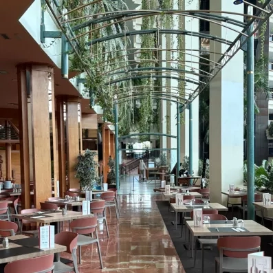 Une grande salle de restaurant élégante sous une impressionnante structure de verrière cintrée.