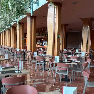 Un bar intérieur chaleureux avec de grandes colonnes en bois et de nombreuses tables.