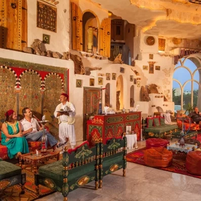Restaurant traditionnel avec murs en pierre, tapisseries géométriques et tables élégamment dressées.