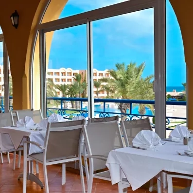 Restaurant avec des tables dressées avec la vue sur la piscine 