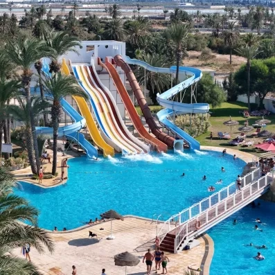 Grands toboggans colorés et piscine de réception de l'aquapark du One Resort Jockey à Monastir, idéal pour les familles.