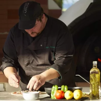 Un chef cuisiner entrain de faire le découpage d'une pizza sur le comptoir  
