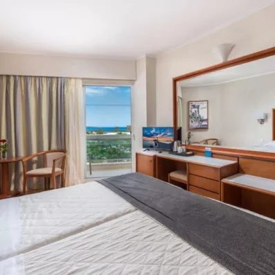 La chambre avec grand lit double, une coiffeuse en bois et un grand miroir, terrasse avec vue sur mer  