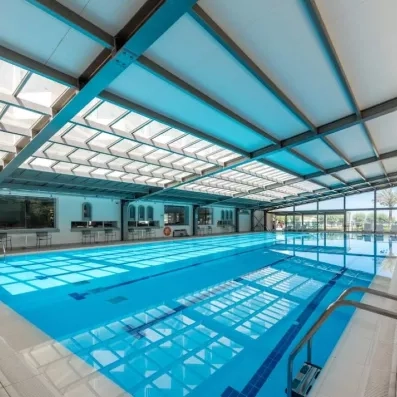 piscine intérieure couverte et avec des vitres et un bar autour