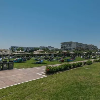 le jardin autour de la piscine avec une allée au milieu et des transats pour bronzer