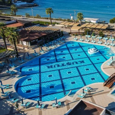 Une vue aérienne de la piscine bordée de transats, située juste en face de la mer azur.