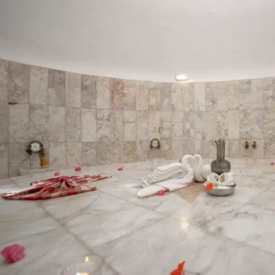 Un intérieur de hammam traditionnel tout en marbre, orné de serviettes pliées.