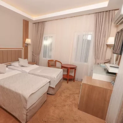 Une chambre avec deux lits simples, une moquette et un petit guéridon.