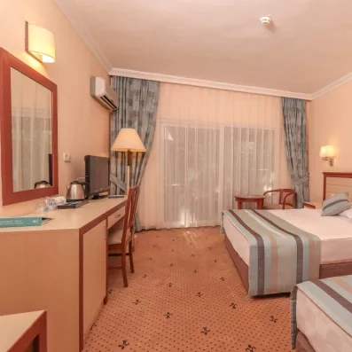 Une chambre spacieuse avec un lit double et un lit simple et un accès balcon.