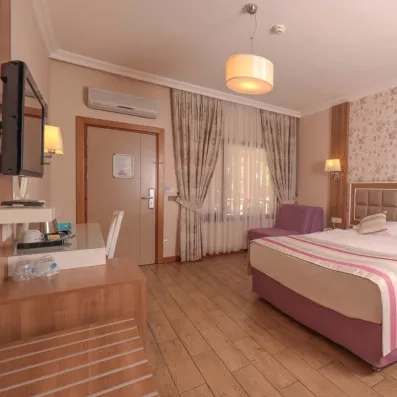 Une chambre lumineuse avec un lit double et un petit coin salon avec des fauteuils.