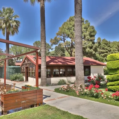 Le charmant pavillon en bois entouré de palmiers et de massifs de roses fleuries.