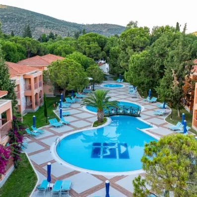 Une grande piscine, entourée de transats et nichée au cœur des bâtiments ocres du club.