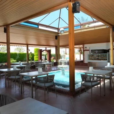 Un café abrité sous une structure en bois avec une fontaine centrale et un dôme vitré.