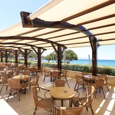 Une terrasse ombragée par des voiles blanches, offrant une vue paisible sur la mer.